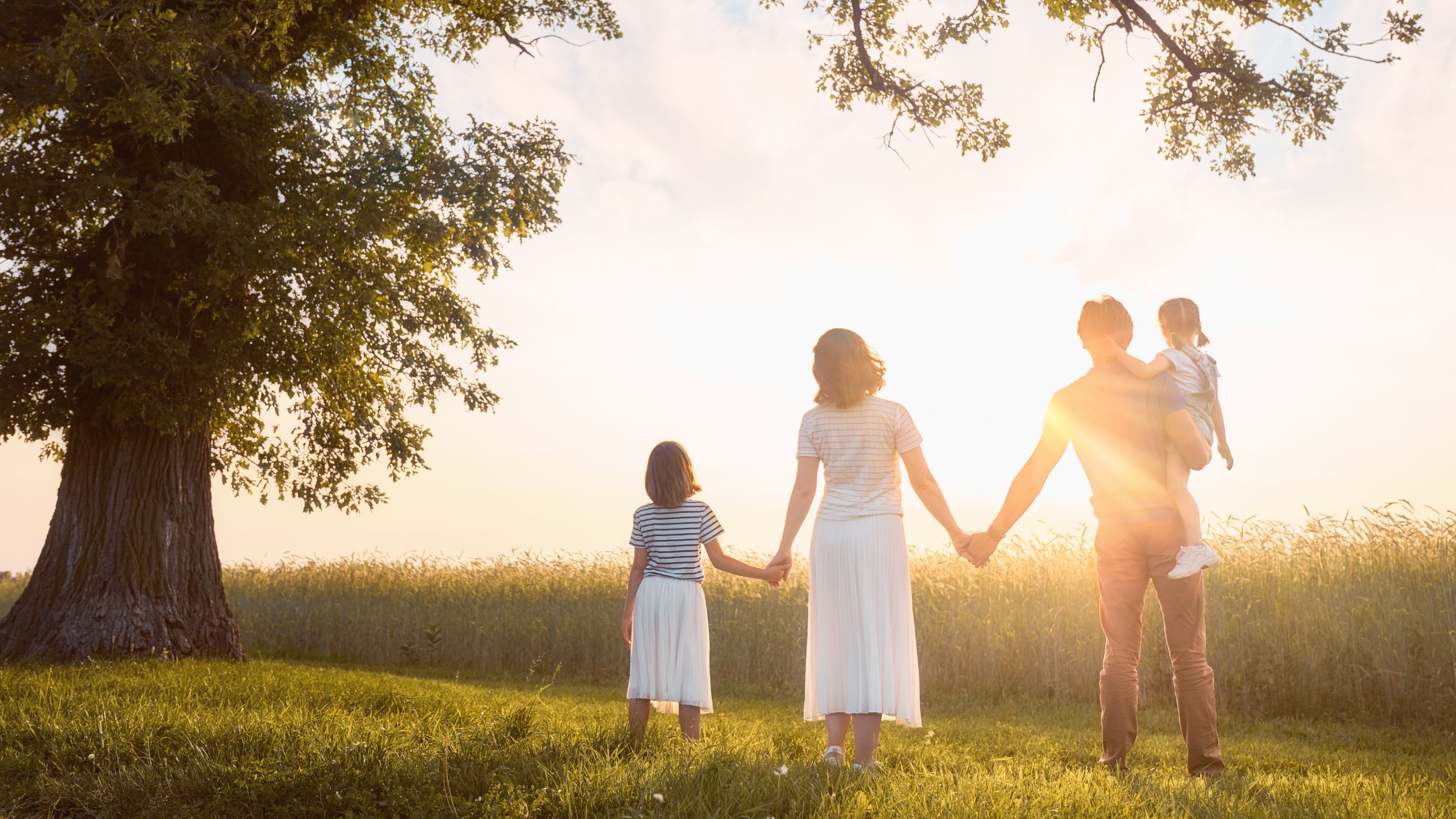 Una familia de la mano mira el horizonte al atardecer