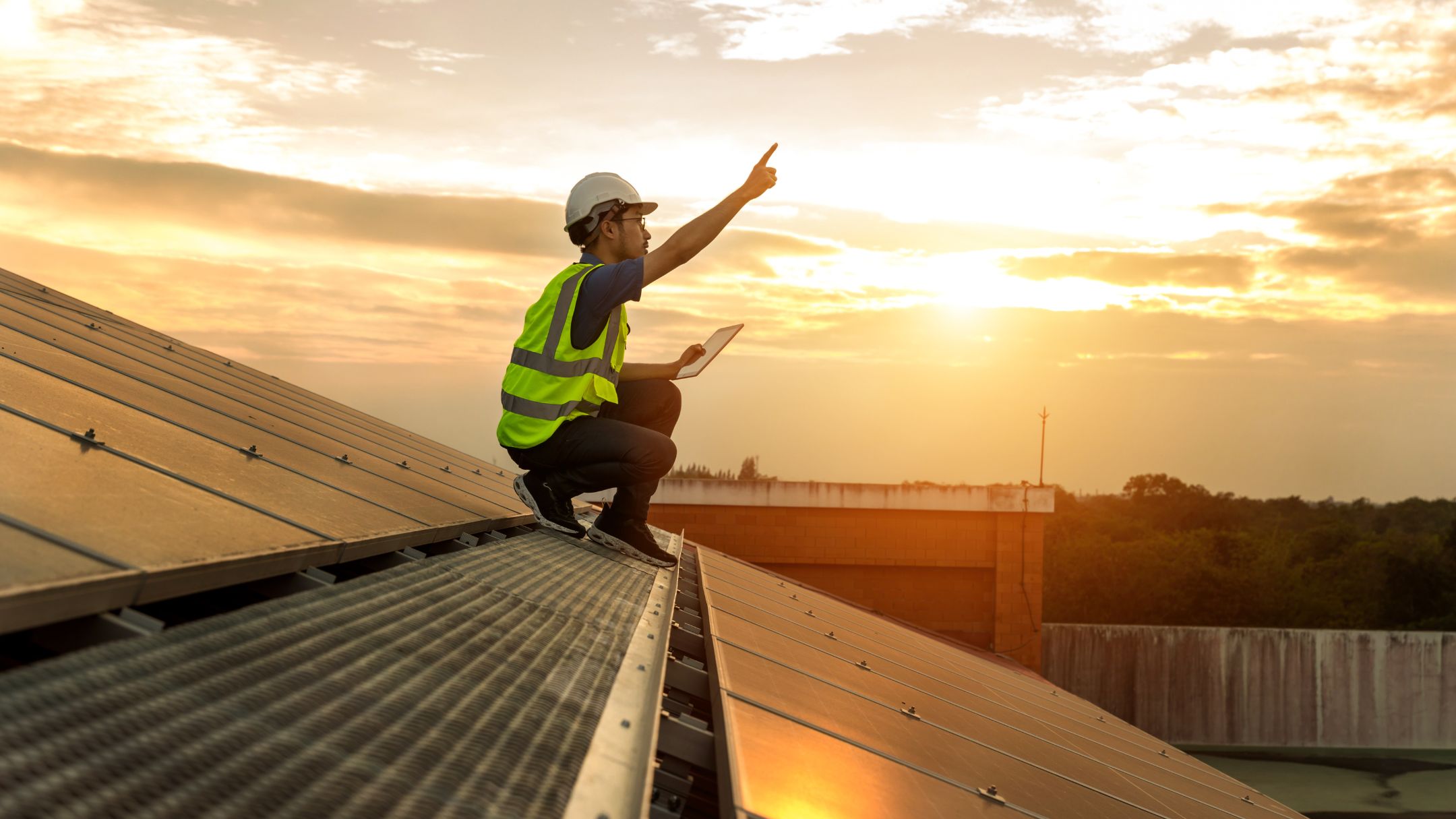 Instalador de SolarPower sobre un techo con paneles solares al atardecer
